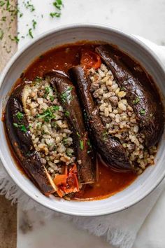 two stuffed eggplant in a bowl with rice and garnish on the side