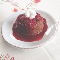 a small dessert on a white plate sitting on a floral tablecloth with red flowers