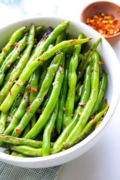 a white bowl filled with green beans and seasoning