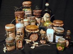 an assortment of bottles and jars with labels on them sitting on a black cloth covered surface