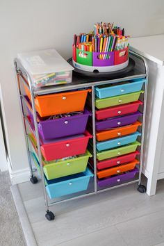 a metal cart filled with lots of colorful plastic containers and pencils on top of it