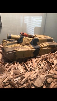 a toy tank sitting on top of wood shavings