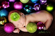 a baby is sleeping with christmas ornaments around her and wearing a flower in her hair