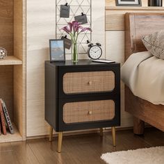 a nightstand with two drawers and an alarm clock on it in a small room next to a bed