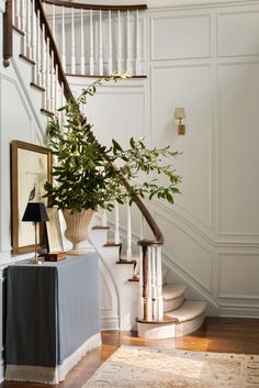 a plant in a vase sitting on top of a table next to a stair case