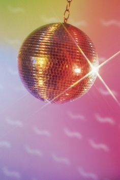 a disco ball hanging from a chain on a colorful background with white dots and lines