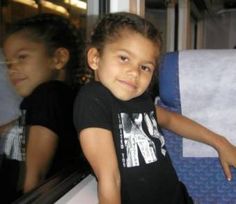 two young children sitting on a bus looking out the window at something in the distance