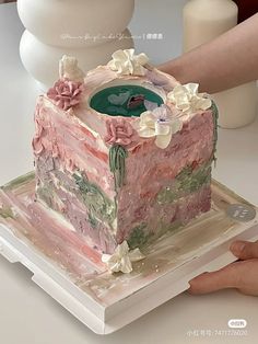 a cake that has been decorated with flowers on it and is being held by someone's hand