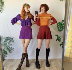 two women are standing in front of a mirror taking a selfie with their cell phones