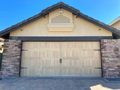 a house with two garage doors and brick walls