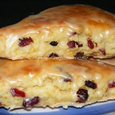 two scones sitting on top of a plate covered in icing and cranberries