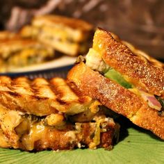 two grilled sandwiches sitting on top of a green plate next to other food items