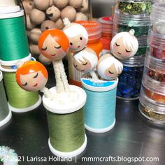 several spools of thread with dolls on them sitting next to other spools