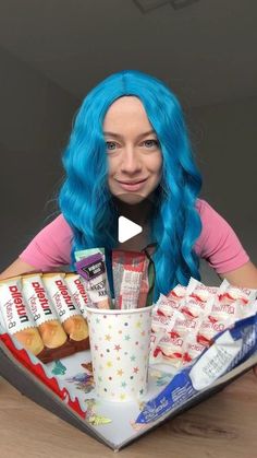 a woman with blue hair sitting at a table in front of a tray full of food