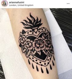 a black and white tattoo on the leg of a woman with flowers in an ornate heart