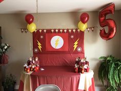 a birthday party with balloons and decorations on the wall, including a red table cloth