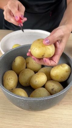 a woman is peeling potatoes in a bowl