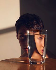 an instagram photo with a glass of water in the foreground and a woman's face behind it