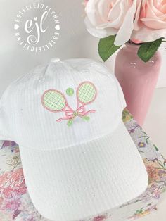 a white hat with a pink tennis racket embroidered on the front and back side