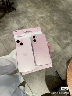 someone holding up two new iphones in their hands, one is pink and the other is white