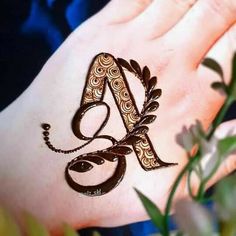 a henna design on someone's hand with flowers in the foreground and leaves around it