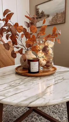 a white marble table topped with a vase filled with flowers and candles on top of it