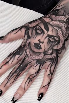 a woman's hand with black and white tattoos on it, including a snake