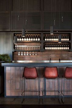 a bar with three red chairs and bottles on it