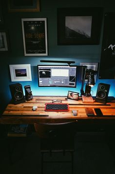 a computer desk with speakers and a keyboard on it in front of some framed pictures