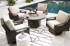 an outdoor table and chairs near a pool with a rug on the floor next to it