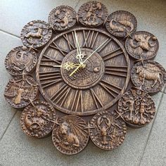 a clock made out of wood with zodiac signs on the face and numbers around it