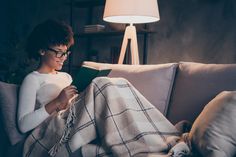 a woman sitting on a couch reading a book