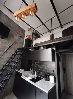 a kitchen area with sink, stove and stairs leading up to the loft bed room