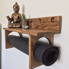 a wooden shelf with a buddha statue on it and a roll of yoga mat underneath