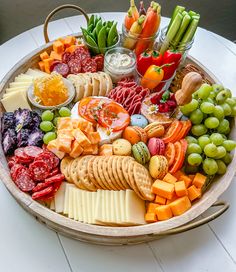 a platter filled with different types of cheeses, crackers and fruit on a table