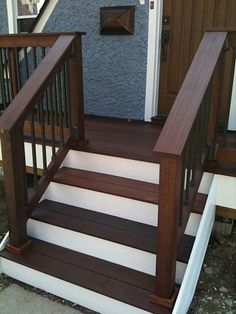 there is a set of stairs leading up to the front door on this house with wood handrails