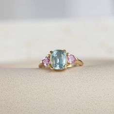 an aqua and pink tourmaline ring sitting on top of a white countertop