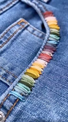 the back pocket of a pair of blue jeans with multicolored fringes on it