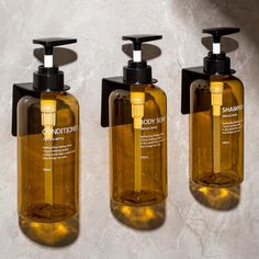 three brown soap dispensers sitting on top of a white marble countertop