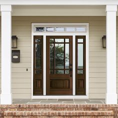 the front door of a house with two sidelights and brick steps leading up to it