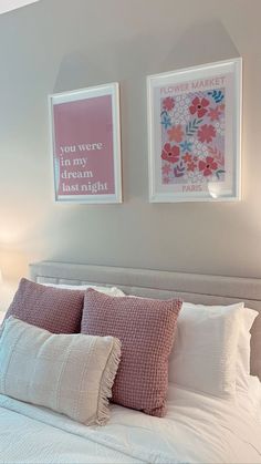 two framed pictures hang above a bed with white linens and pink pillows on it