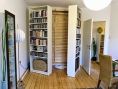 a living room filled with lots of books on top of a hard wood floored floor