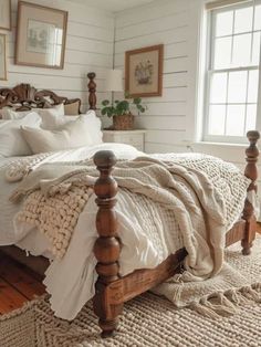 a bedroom with white walls and wooden bed frame, pillows and blankets on the bed