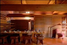 a dining room with wood paneling and wooden chairs around a table that is surrounded by stools