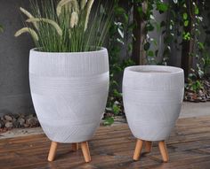 two white planters sitting on top of a wooden floor