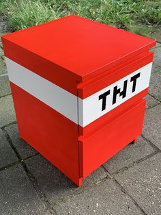 a red and white box with the word tht on it's side sitting on a sidewalk