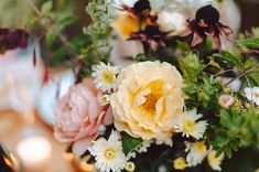 a bouquet of flowers sitting on top of a table next to a vase filled with white and pink flowers