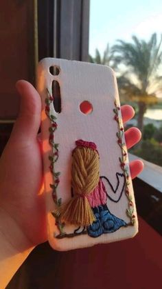 someone is holding up their phone case to show the embroidery work on it's back