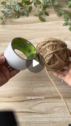 someone is holding a roll of twine with a tape attached to it and another person's hand reaching for the rope