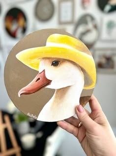 a hand holding up a sticker with a duck wearing a hat on it's head